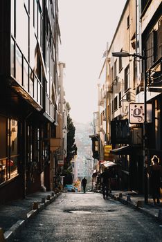 A picturesque narrow street with sunlit buildings and people strolling in the alley.