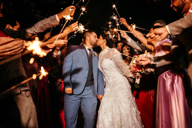 Wedding Guests Holding Sparklers For Kissing Couple