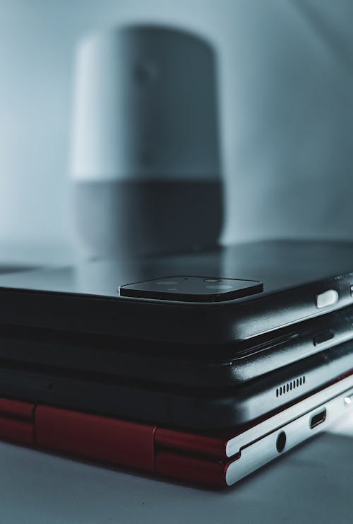 Cellphone on Stack of Black and Red Laptops 