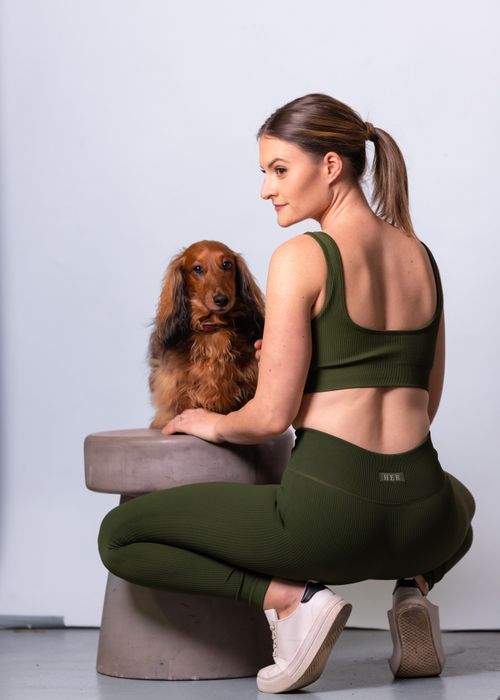 Free Woman in workout attire crouching beside a dachshund dog indoors. Stock Photo