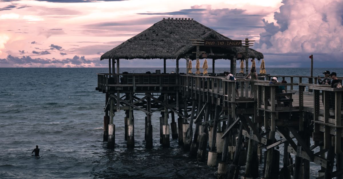Cocoa Beach pier at sunset with tiki hut and ocean views in Florida, capturing a calm seaside ambiance.