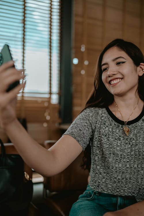 Woman in Gray Shirt Holding a Smartphone