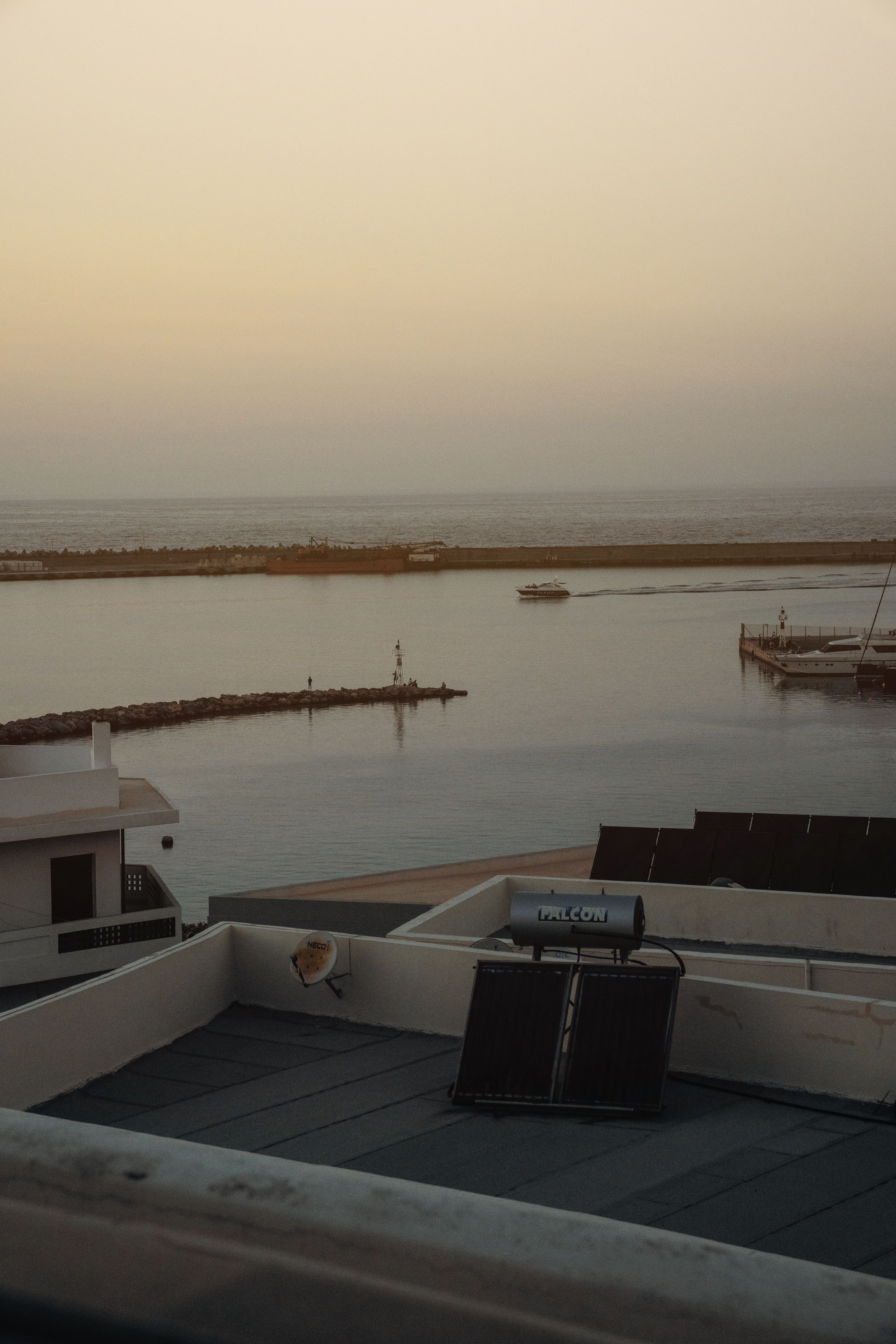 Serene coastal scene at sunset featuring a rooftop solar panel and tranquil waters.