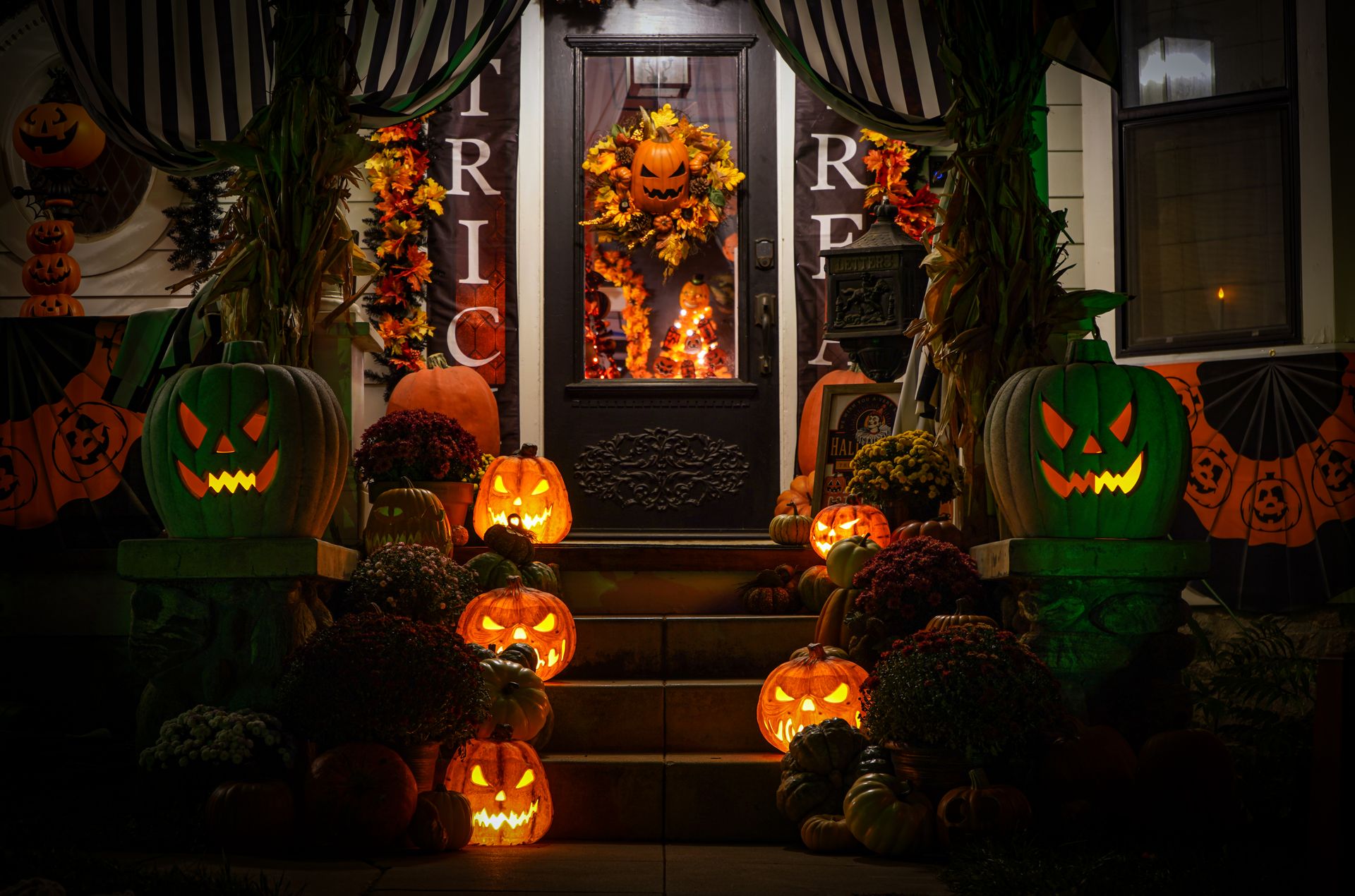 Decorated porch with glowing jack-o'-lanterns on Halloween night.