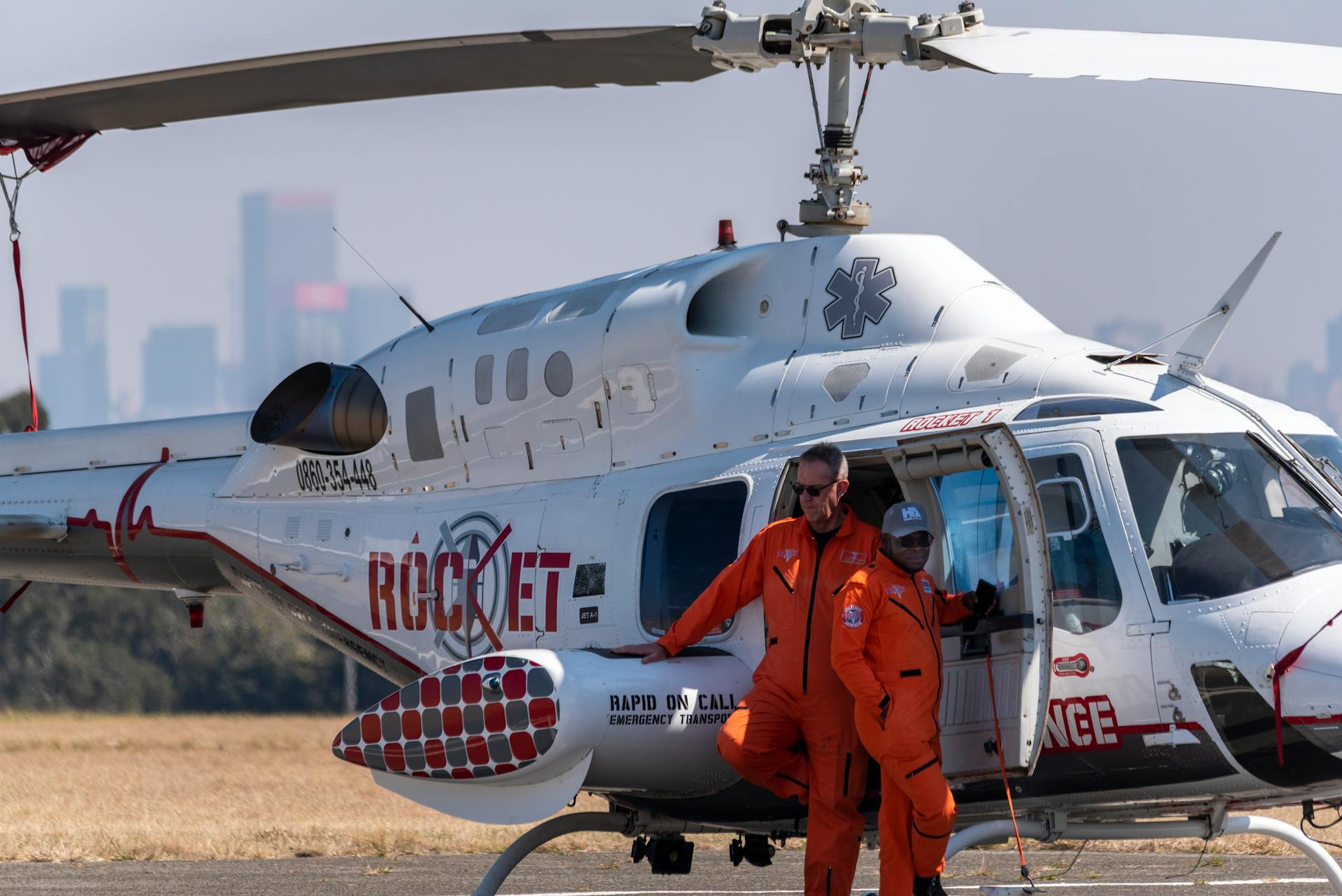 Medical crew standing beside an emergency helicopter on a sunny day.