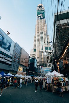 Vibrant street market under the iconic Baiyoke Tower II in Bangkok, Thailand.