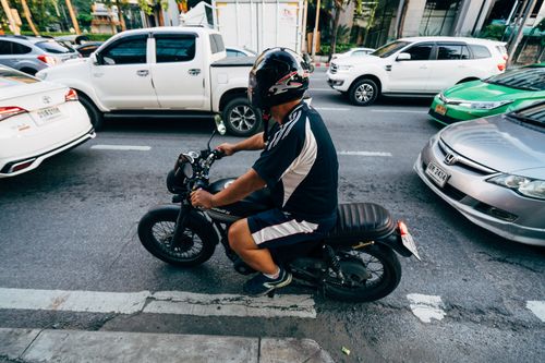 Free Motorcyclist navigating urban traffic on a busy city road. Stock Photo