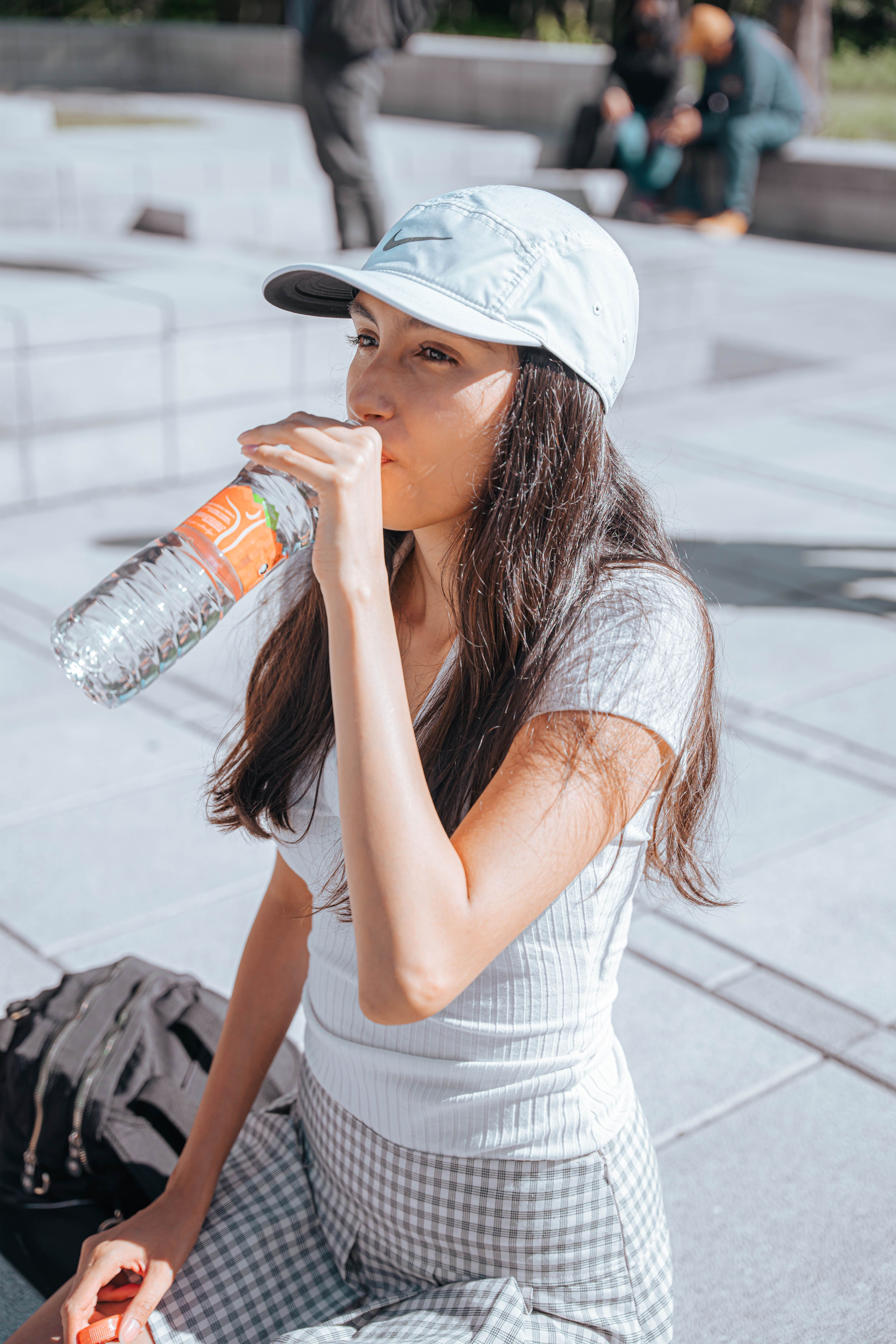 Perempuan minum air di luar ruangan pada siang hari