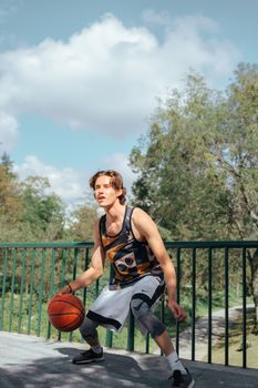 A young man playing basketball in a park, showcasing athleticism and sportswear style.