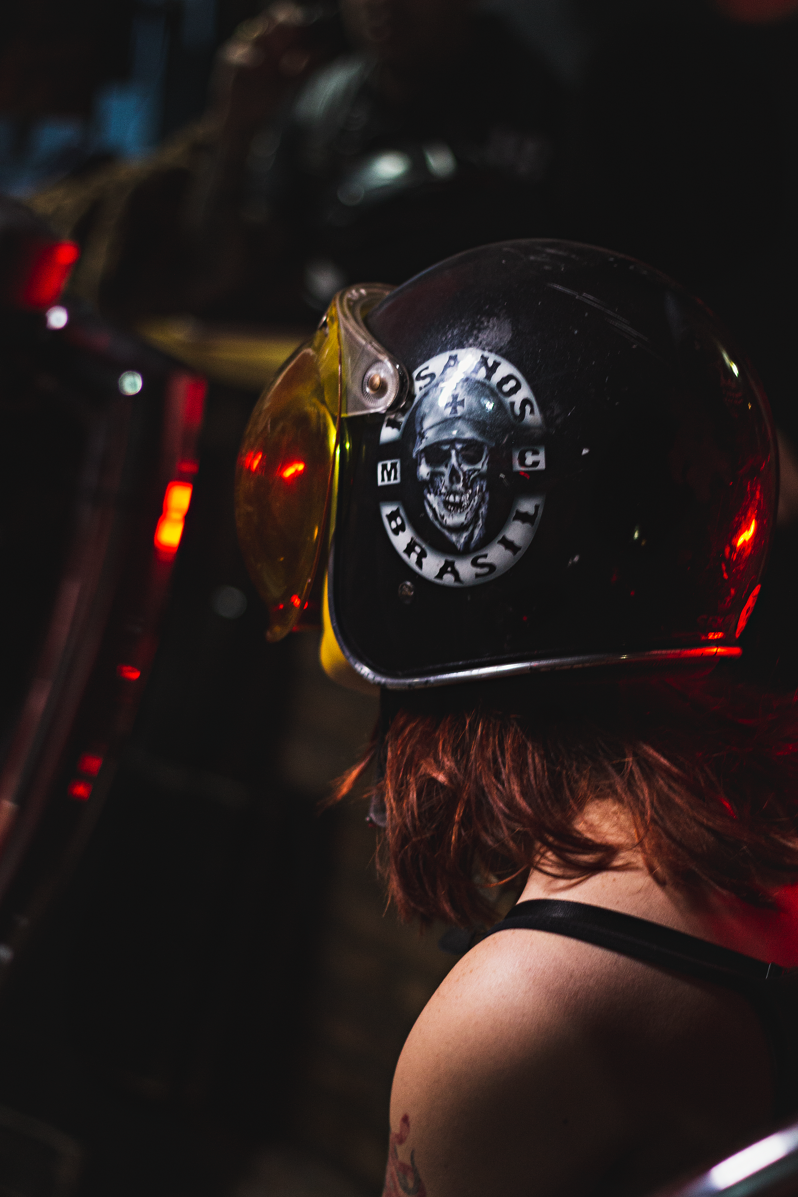 A woman wearing a skull-themed helmet rides a motorcycle at night, emphasizing safety and style.