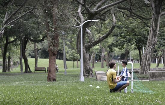 A father and son enjoy time together in a lush green park setting.