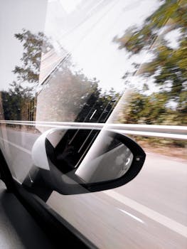 Car side mirror reflects road motion in rural Turkey, depicting travel energy.