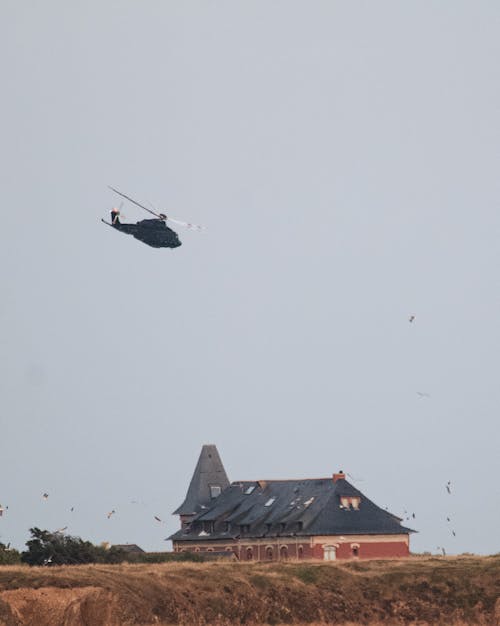 A Helicopter Flying Above Brown Field Under Blue Sky