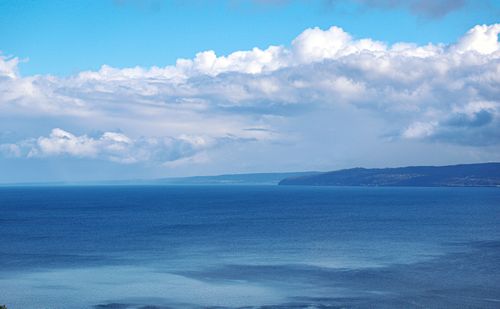 Free A breathtaking aerial view of the expansive blue ocean meeting the sky filled with clouds. Stock Photo