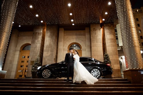 Bride and Groom Posing on Grand Entrance Door Outside a Building