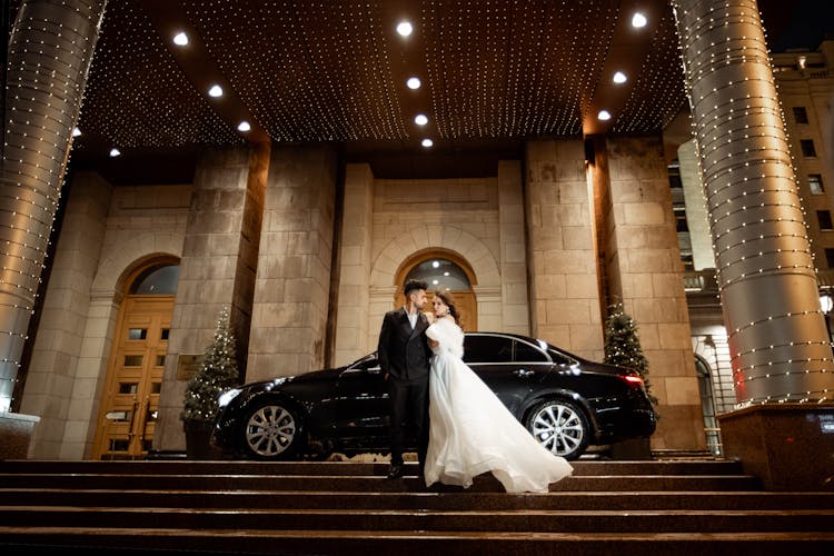 Bride And Groom Posing On Grand Entrance Door Outside A Building