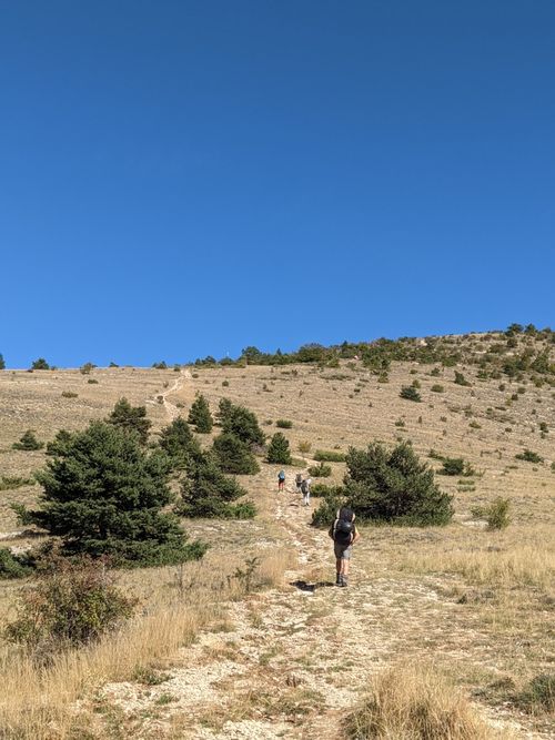Free Group of hikers on a dry mountain trail under a clear summer sky. Stock Photo