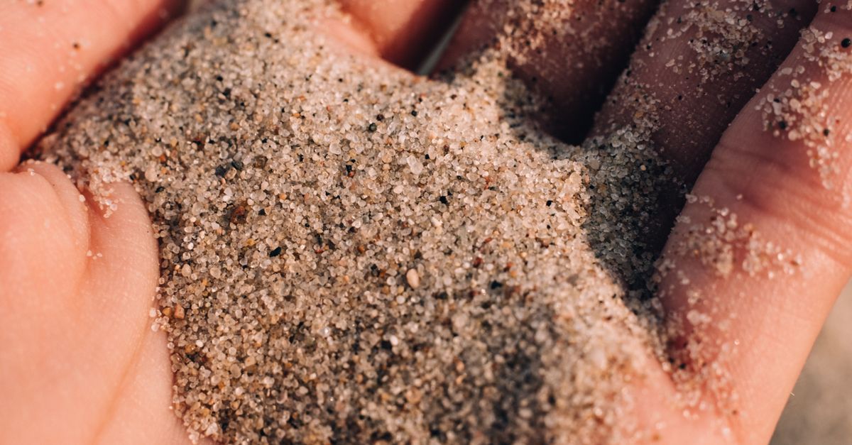 Detailed close-up of sand slipping through fingers on a warm sunny day. - Evidence evidence guide for bamboo silica skin randomized trial