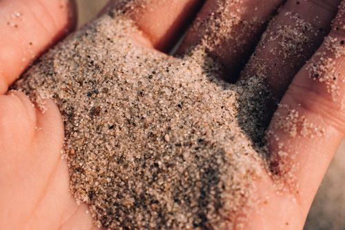 Free Detailed close-up of sand slipping through fingers on a warm sunny day. Stock Photo