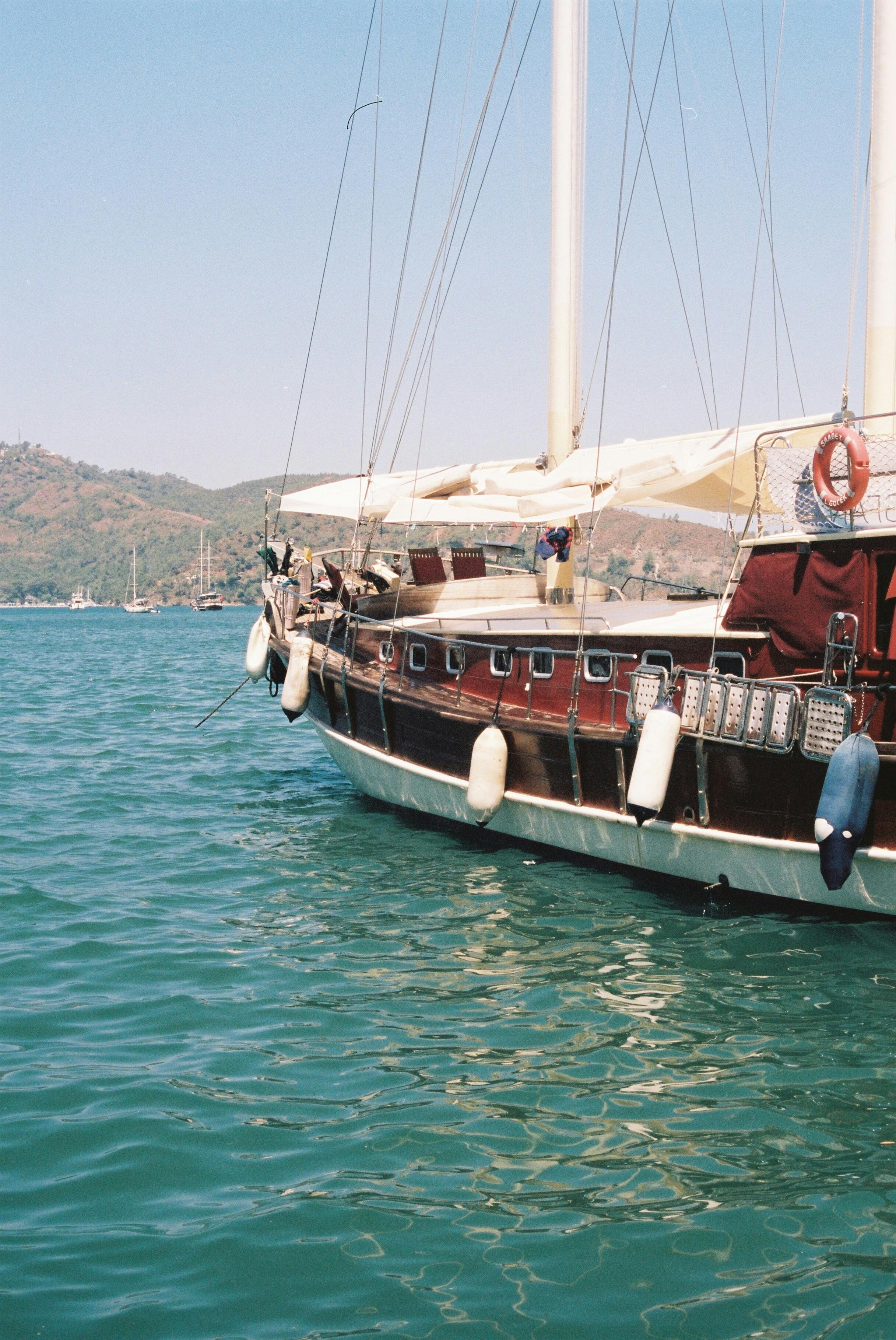 A classic sailboat docked in a tranquil harbor on a clear day, perfect for leisure activities.