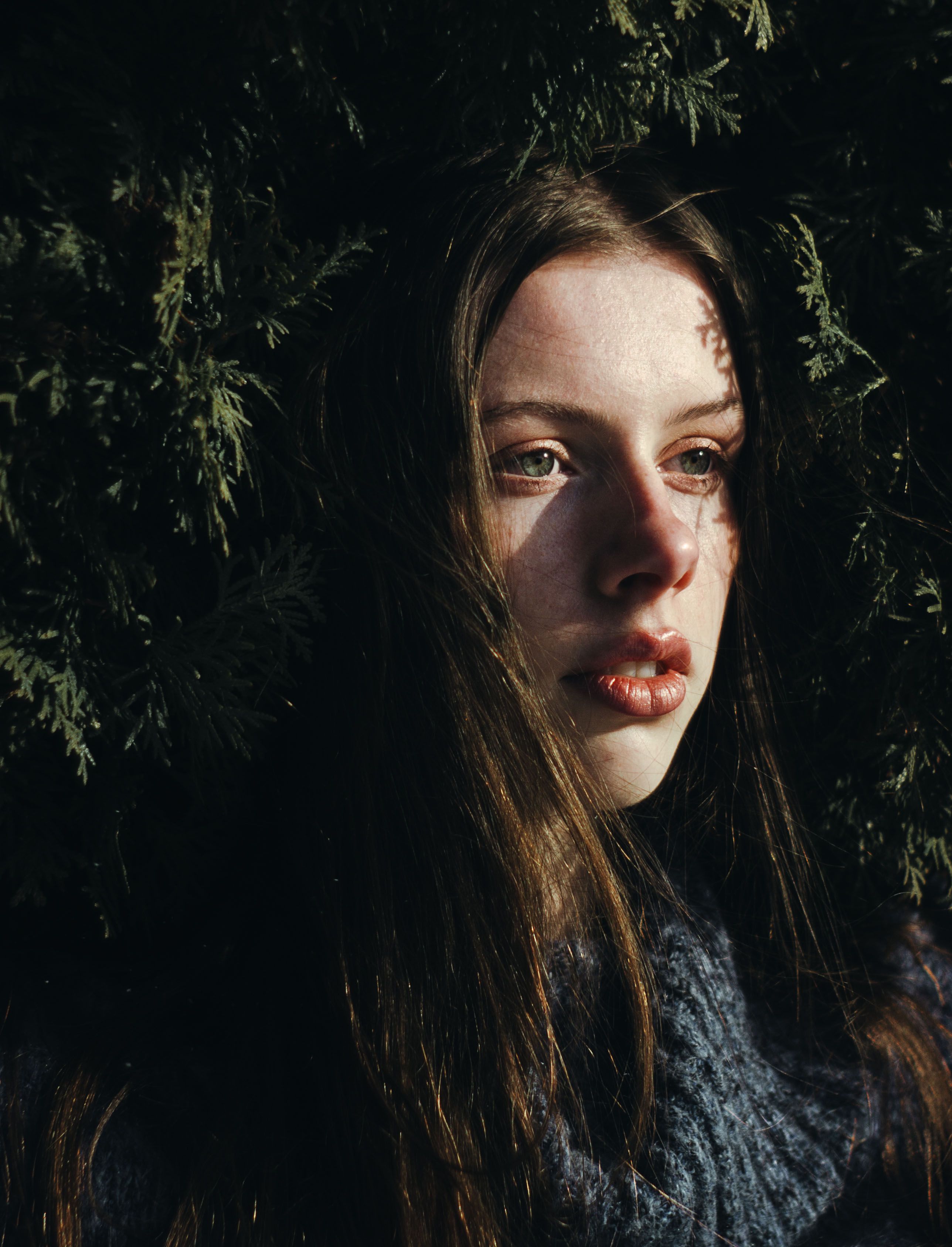 Close-up portrait of a woman looking contemplative among dense foliage