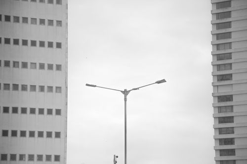 Free Black and white photo of modern skyscrapers with a single streetlight in the foreground, offering a minimalist urban aesthetic. Stock Photo