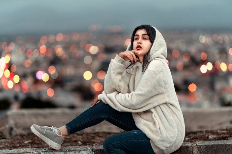 Woman in a white hoodie with a cityscape background
