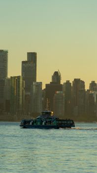 Ferry sailing against the backdrop of Vancouver's skyline at sunset.