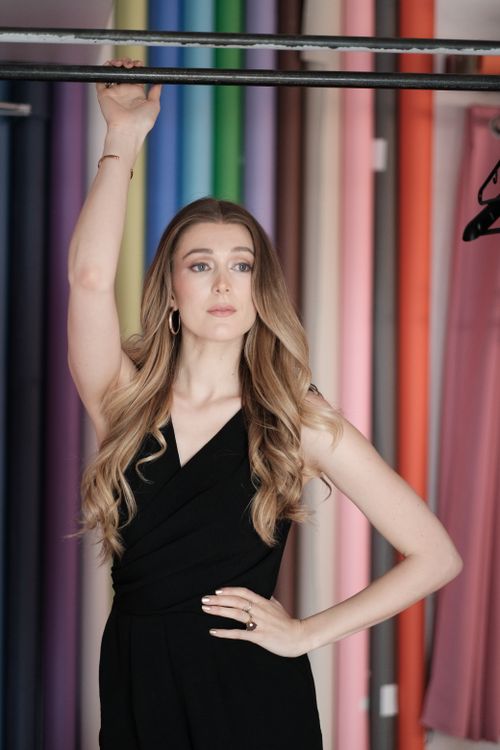 Free Stylish woman with long hair in a black dress posing against a colorful backdrop indoors. Stock Photo