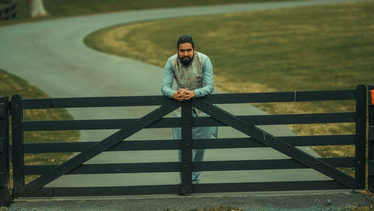 A Man in Nehru Jacket Standing Behind the Wooden Gate · Free Stock Photo