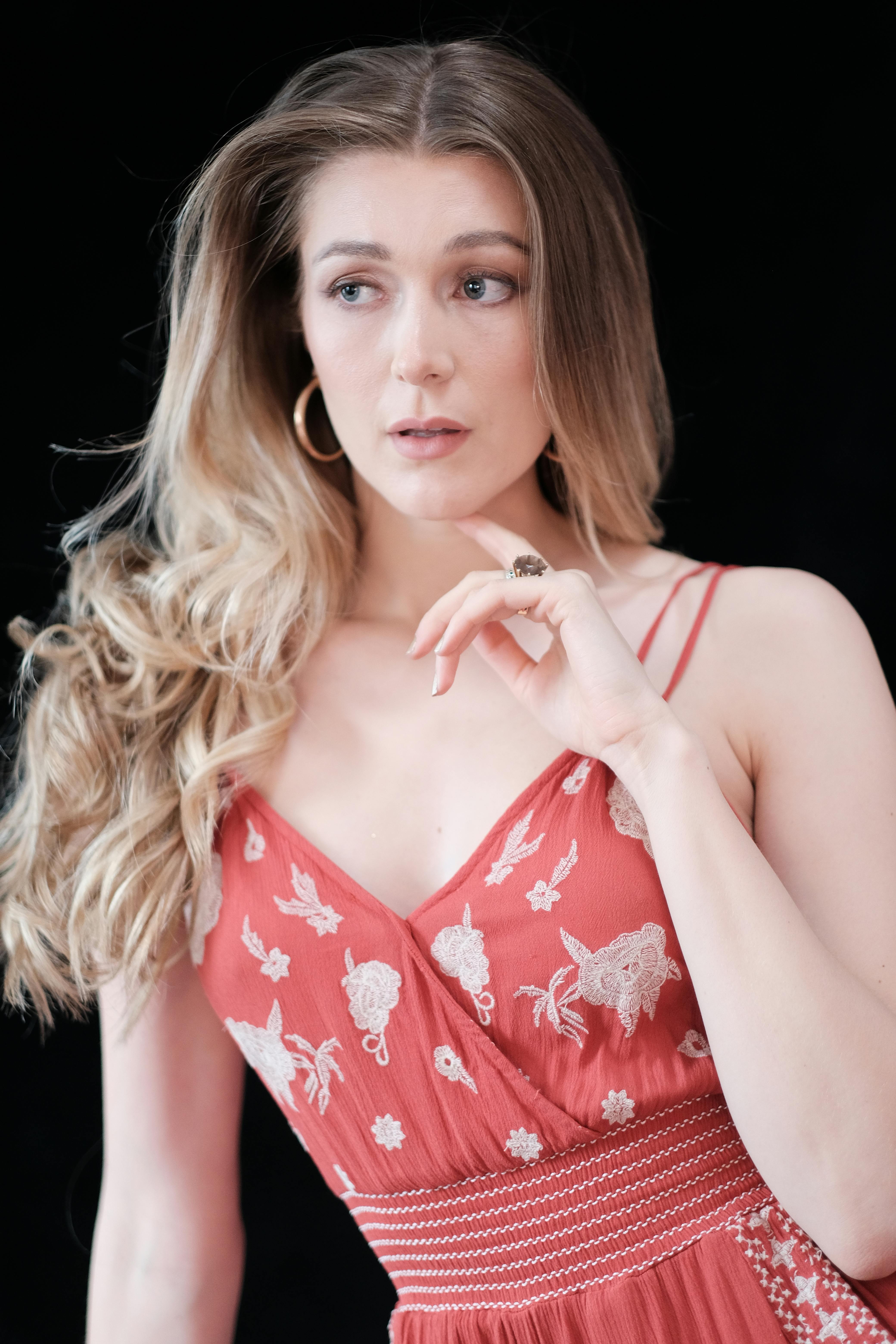 Elegant portrait of a woman wearing a red dress, captured with natural expression against a dark backdrop.