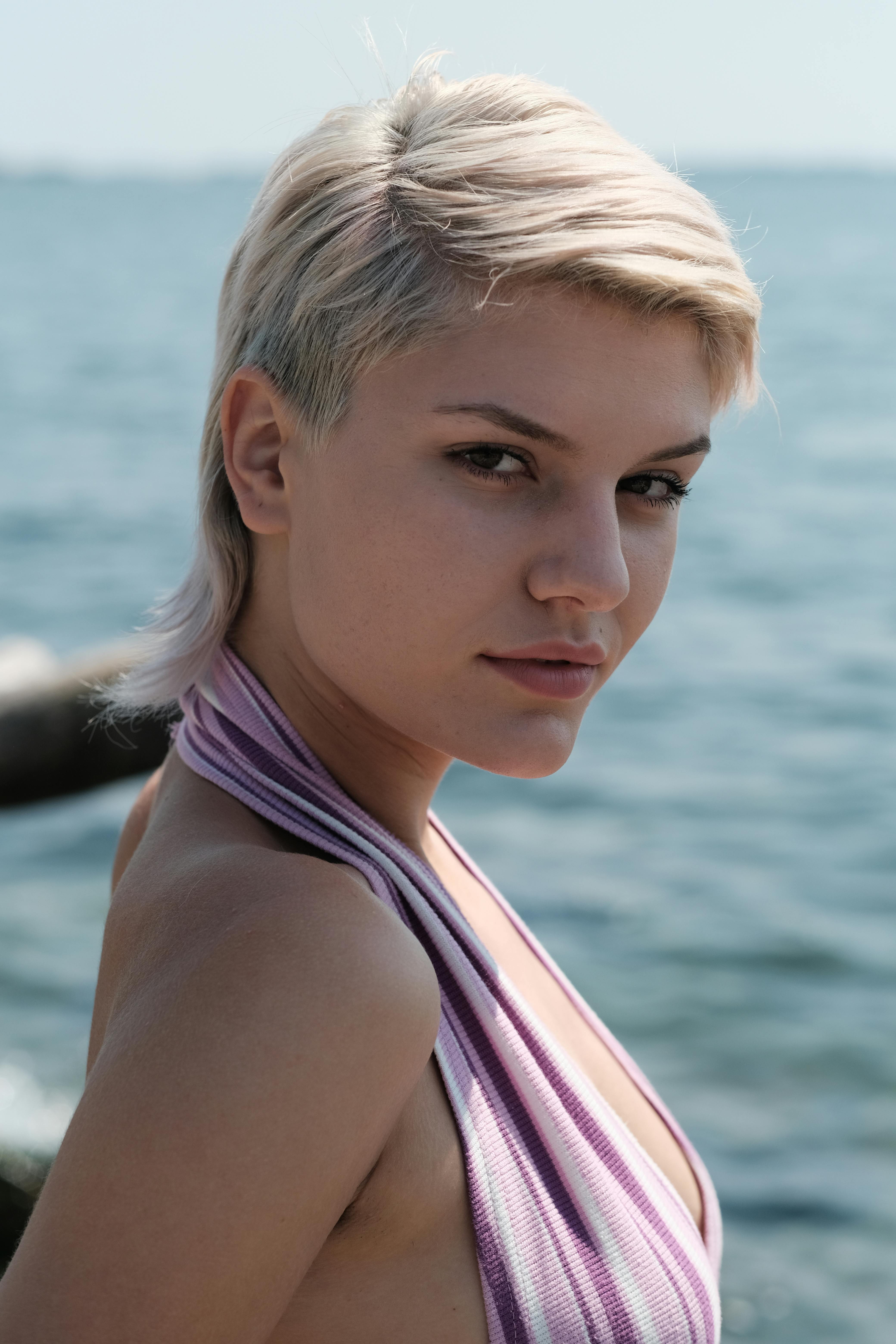 Profile shot of a young woman with short hair against the ocean backdrop.