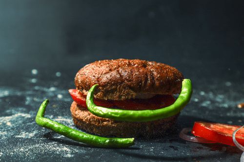 Free Rustic bun with tomatoes and green peppers on dark background. Stock Photo