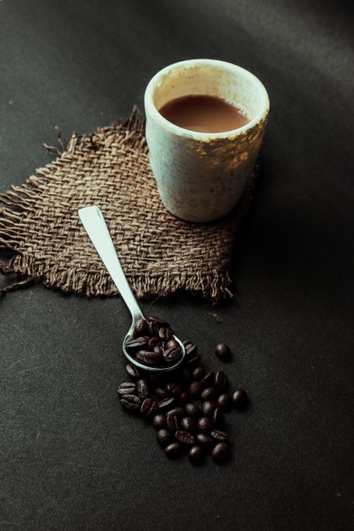 Free A rustic setup of coffee cup with beans and teaspoon on burlap mat, perfect for food and beverage themes. Stock Photo
