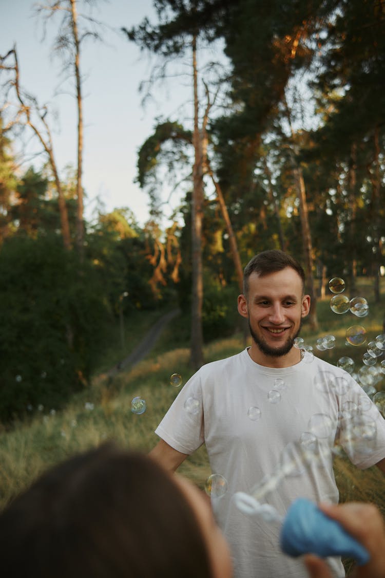 Photo Of A Man Smiling While Looking At Bubbles