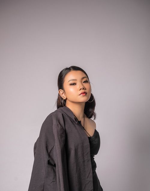 Free Portrait of an Asian woman posing confidently in a trendy black outfit against a gray background. Stock Photo