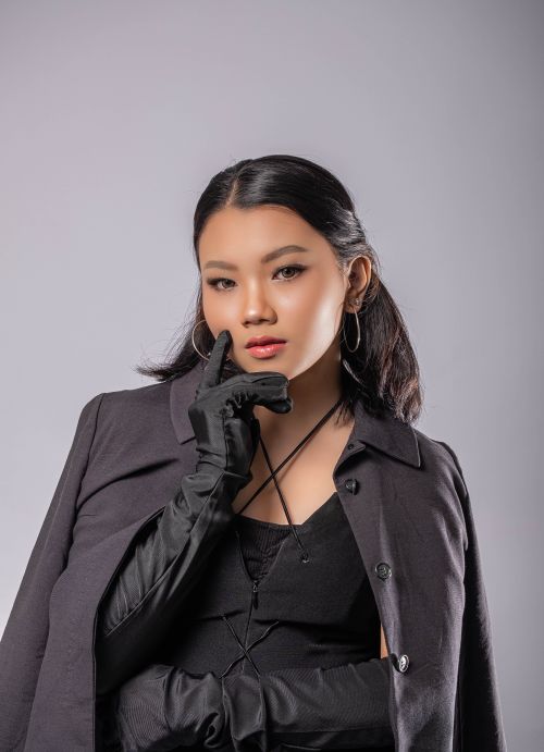 Free Stylish portrait of a young woman wearing black, posing confidently against a gray background. Stock Photo