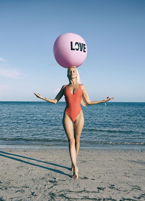 Frau, Die Am Strand Mit Ball Auf Ihrem Kopf Nahe Der Küste Steht