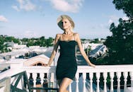 一位穿着黑色连衣裙、戴着帽子的时尚女子在基韦斯特阳光明媚的户外摆姿势