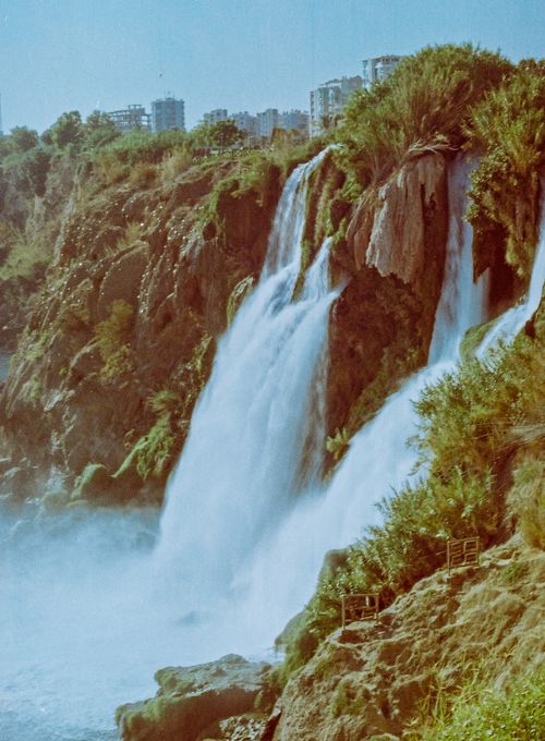 Free Stunning view of a waterfall cascading over rocky cliffs surrounded by lush greenery. Stock Photo