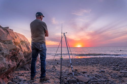 Back View of Fisherman on Sea Shore at Sunset