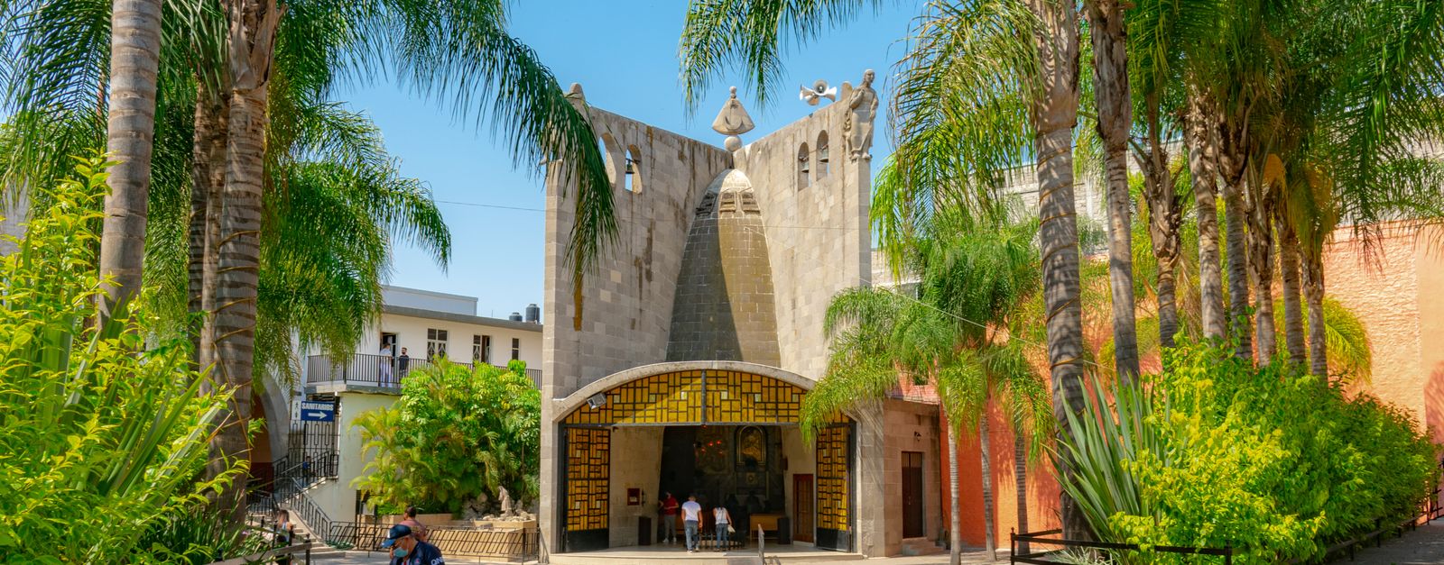 Scenic view of a historic church surrounded by palm trees in San Juan de los Lagos, Mexico.