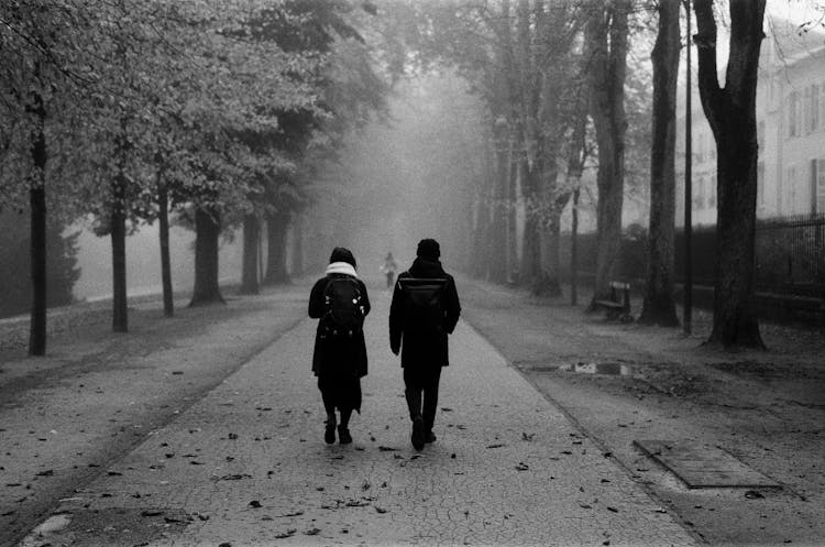 Grayscale Photo Of A Man And A Woman Walking On Road