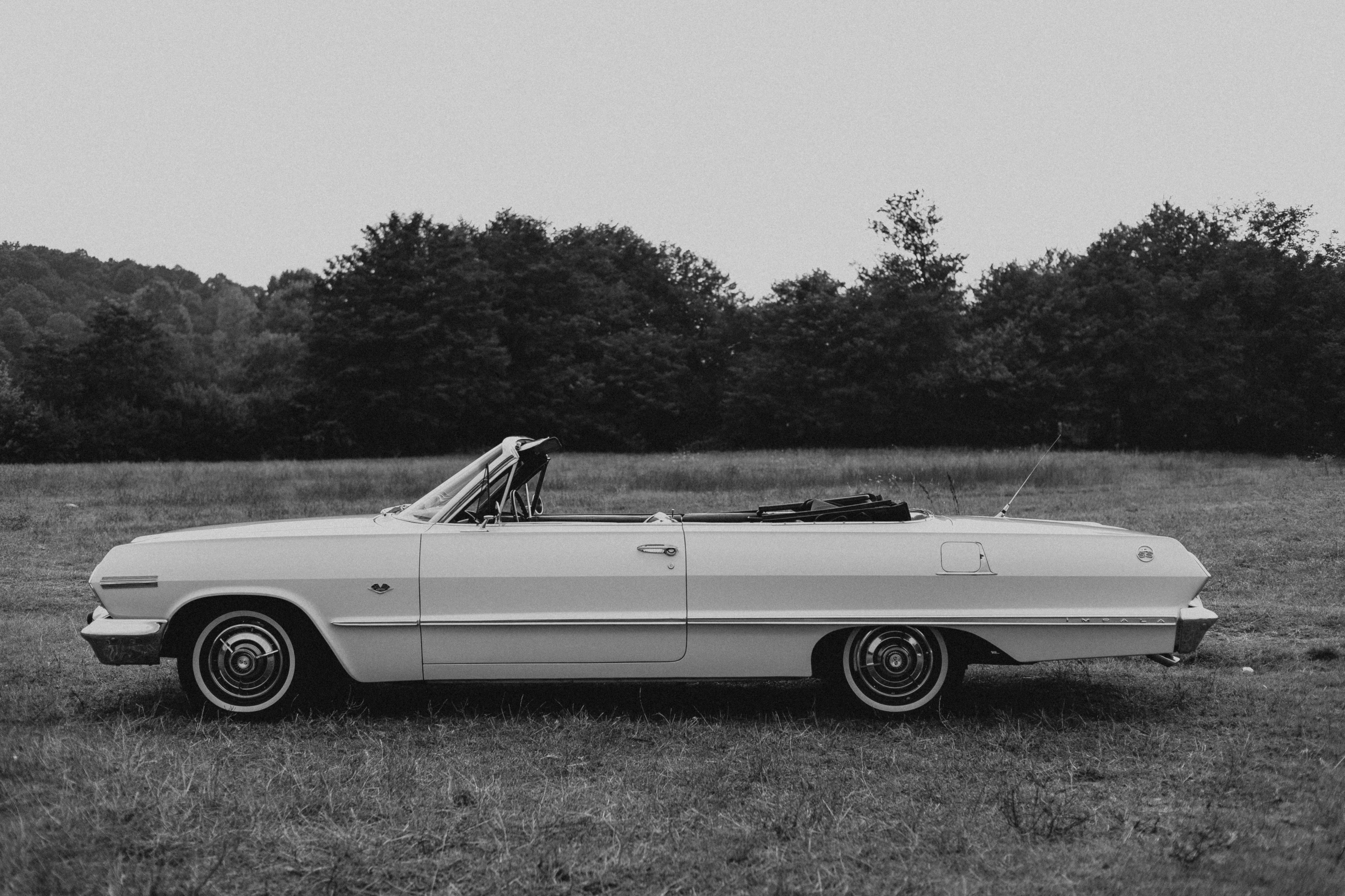 Vintage convertible car parked in open field, captured in black and white for a timeless look.