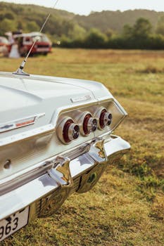 Classic Chevrolet Impala parked in a rural meadow under a clear sky, highlighting its vintage design.
