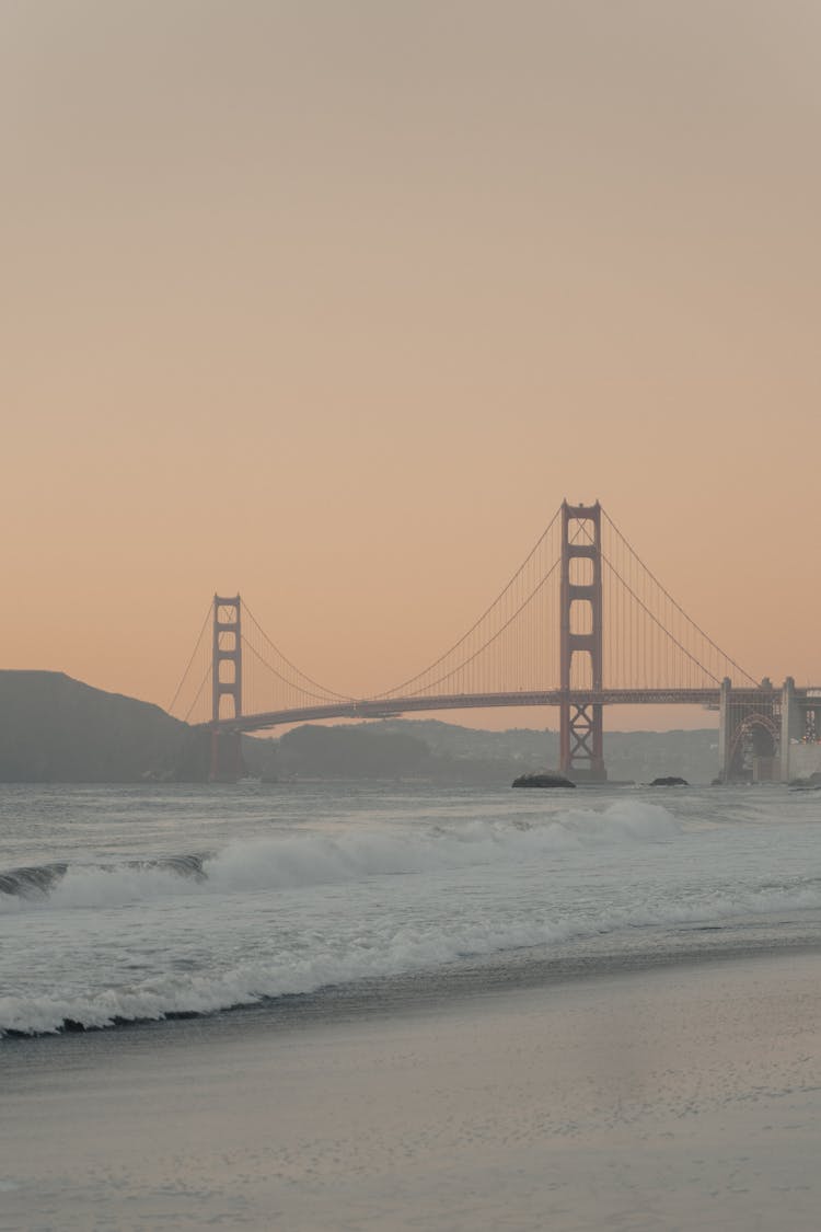 Beige Photograph Of A Suspension Bridge And Rough Water With Waves