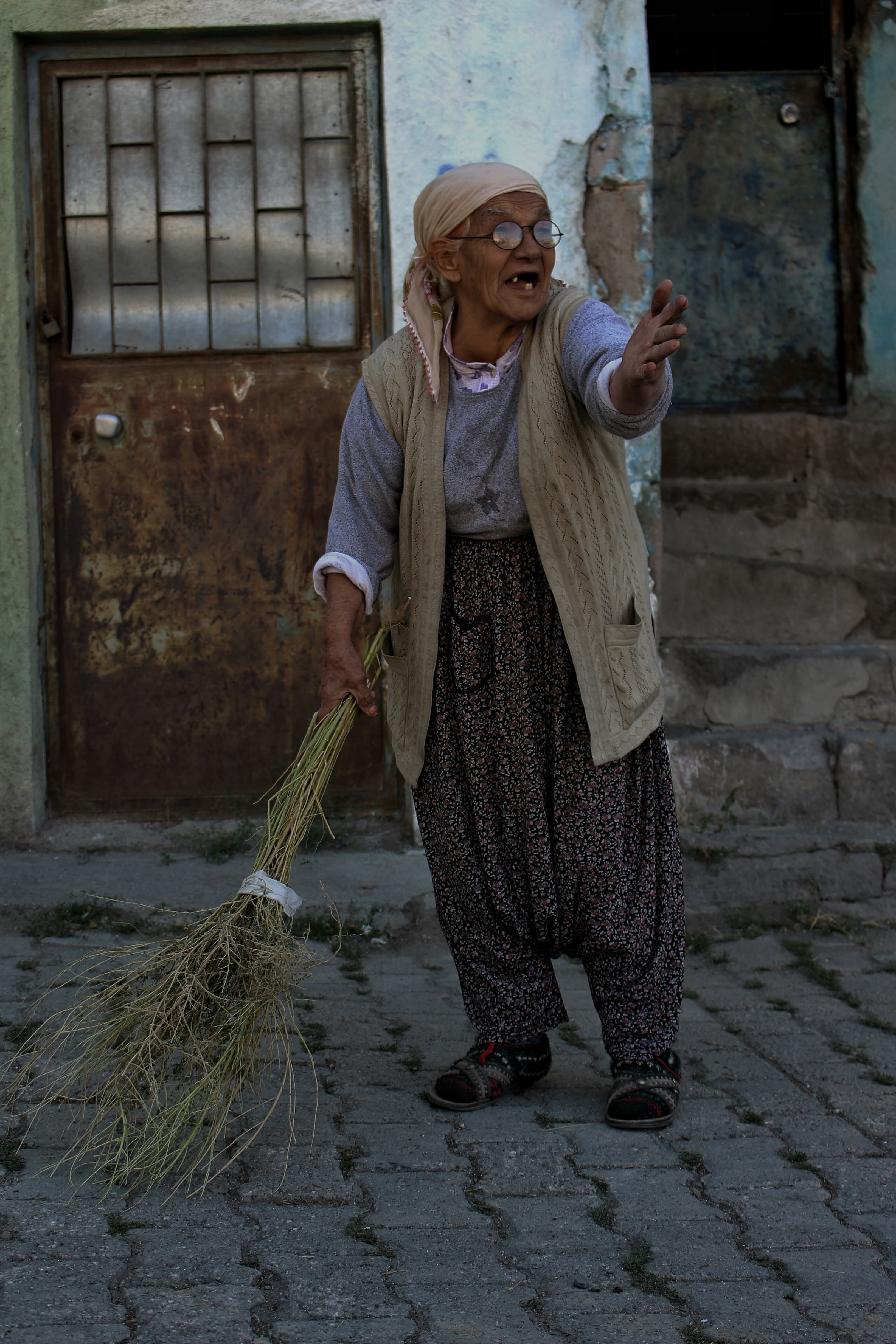 An elderly woman in traditional clothing stands outdoors in Kayseri, Türkiye.