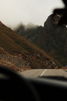 A foggy mountain road seen from a car windshield, capturing a moody, misty atmosphere.