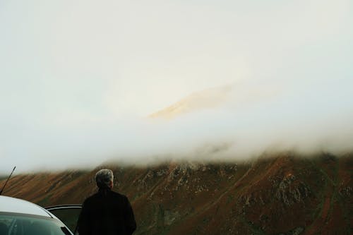 Free Man in Black Jacket Standing Near Gray Car during Foggy Weather Stock Photo