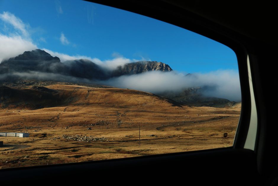 Captivating view of a mountain landscape framed by a car window under a clear blue sky.